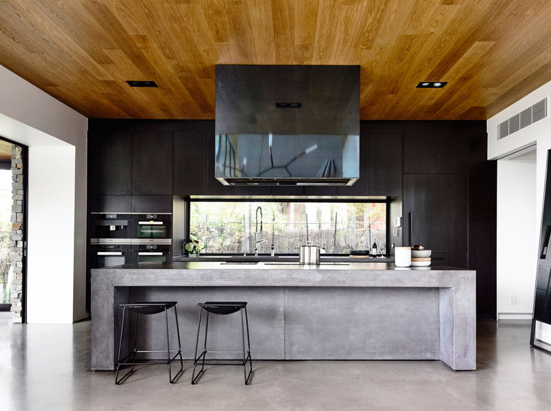 Kitchen Design Idea - 10 Inspirational Examples Of Kitchens With Integrated Fridges // Black cabinets do an excellent job of concealing this fridge by blending the lines and making the whole back wall of the kitchen appear seamless.