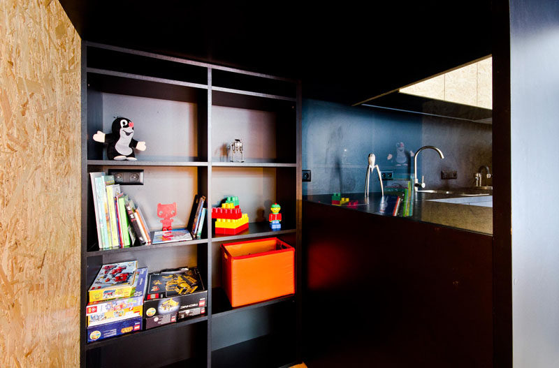 A small hiding room for a child has been tucked into a space behind a desk and a kitchen.