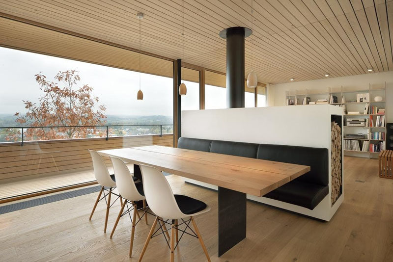 Dining Room Design Ideas - Use Built-In Banquette Seating To Save Space // This black banquette, attached to the back of a room divider (with a fireplace on the other side), matches the black steel legs of the dining table and the black seat pads on the chairs. 