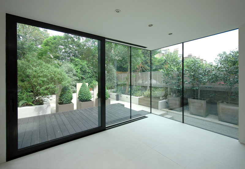 This house extension features corner-to-corner windows and a large sliding door to the patio. Black window and door frames have been used to match to the black wood exterior.