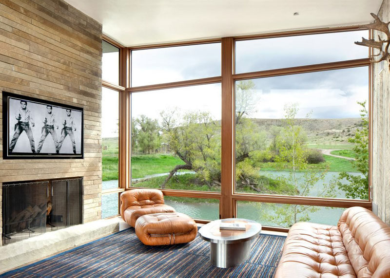 This sitting area with a fireplace has view is of the surrounding hills and river outside.