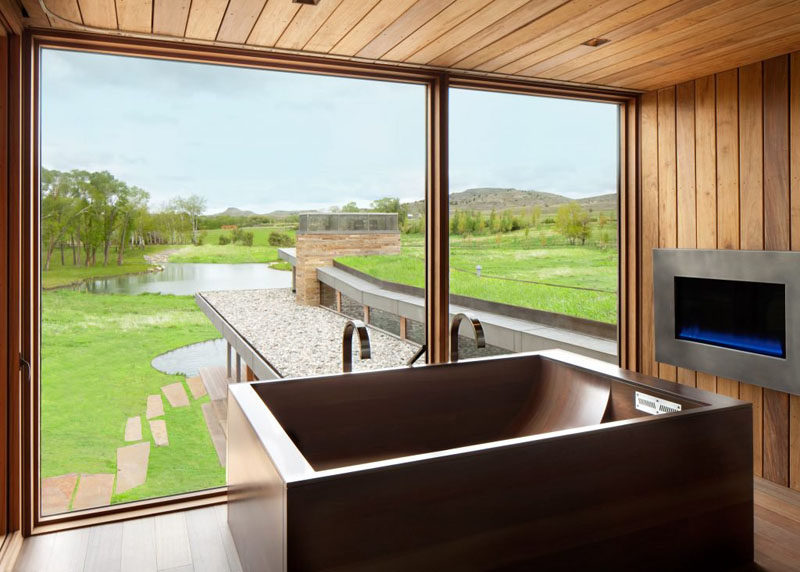 In this bathroom, the wooden bathtub and fireplace make it an idea place to relax and take in the view.
