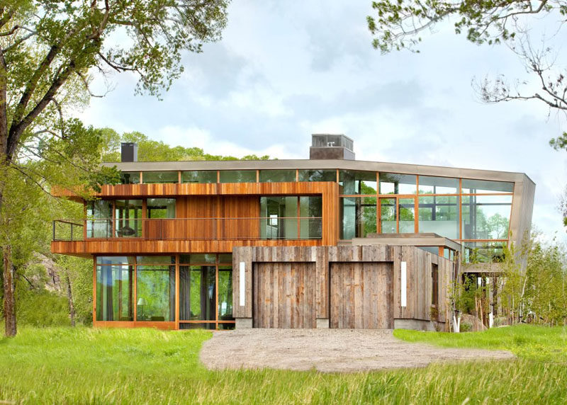 The rear of this contemporary home has two garages covered in wood.