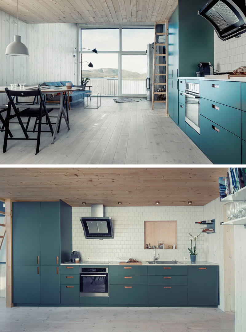 A brightly colored teal blue kitchen with a white tile backsplash lines one wall of this small home.