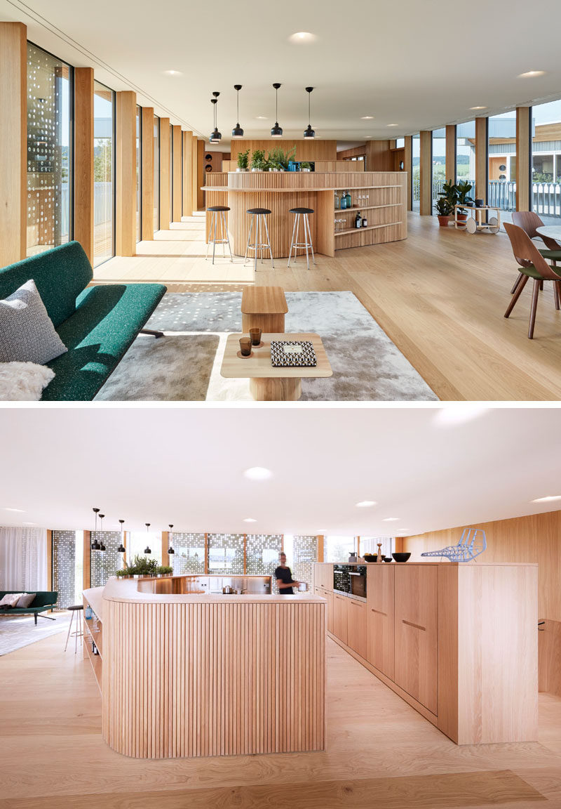 The upper floor of this home is flooded with light from the floor-to-ceiling windows surrounding the living area, and the wood covered curved kitchen has bar seating that transforms into shelving.