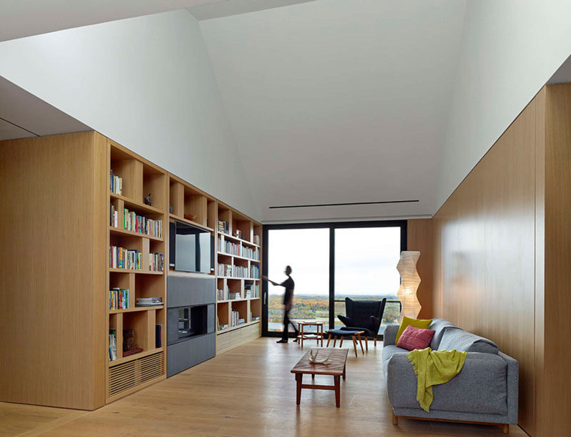 This living area has a wall of shelves filled with books that surround a television and another fireplace.