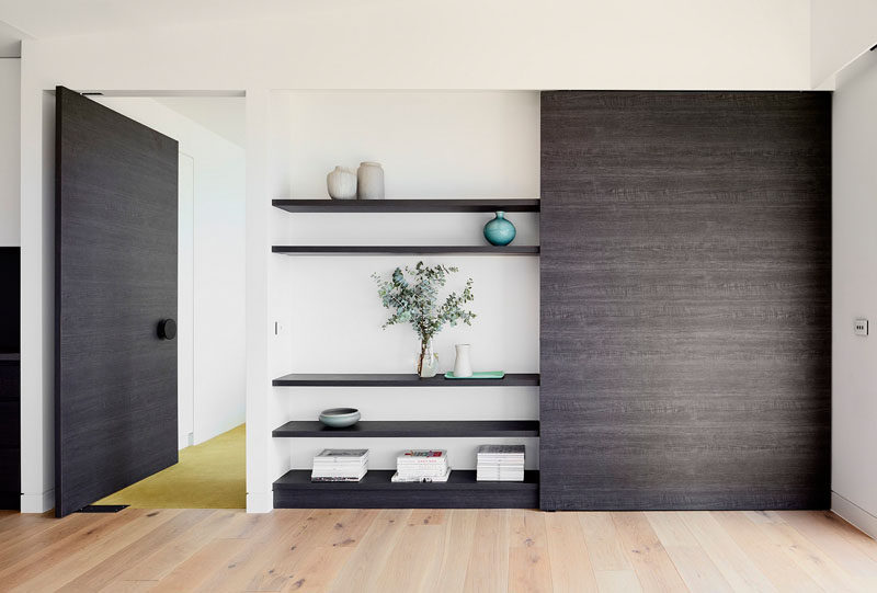 In this house, a custom wooden wall unit displays personal items, and matches the large wooden pivoting door that leads to the bedroom.