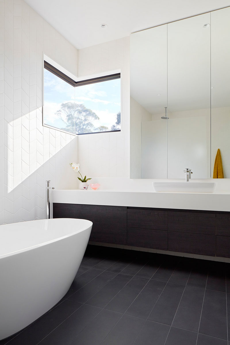 In this bathroom, floor-to-ceiling tiles line the walls, and a corner window allows for lots of light to enter the space.