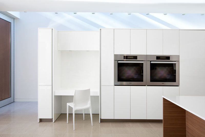 In this mostly white kitchen, a built-in desk has been included in the design that matches the kitchen cabinetry.