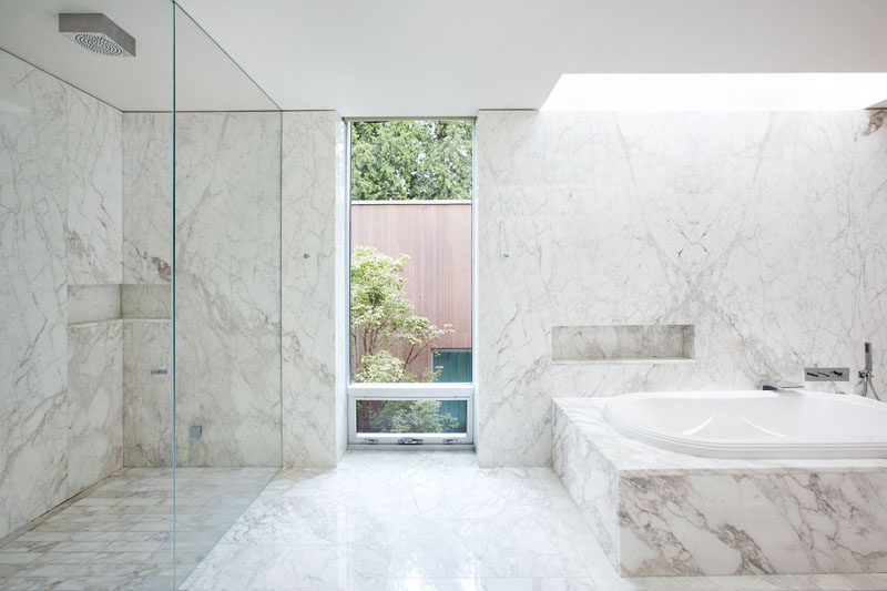 In this bathroom, light colored stone has been used for the walls, flooring and bath/shower surrounds. 