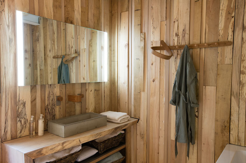 The wall in this bathroom are covered in uneven lengths of wood.