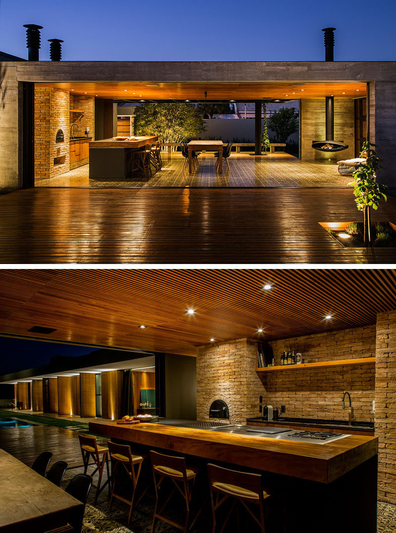 This kitchen has with a built-in fire oven and large island with cooktop and seating. There's also a dining area and a small space to sit by the hanging fireplace.