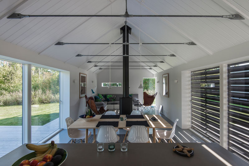 Inside this modern barn, the living, dining and kitchen area all share the same space. White vaulted ceilings and walls give the room a light and lofty feeling.