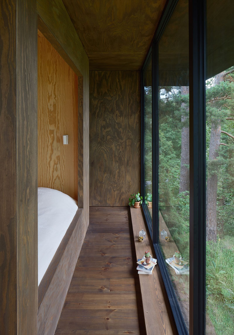 This bedroom in a summer house has views of the garden outside through large floor-to-ceiling windows.