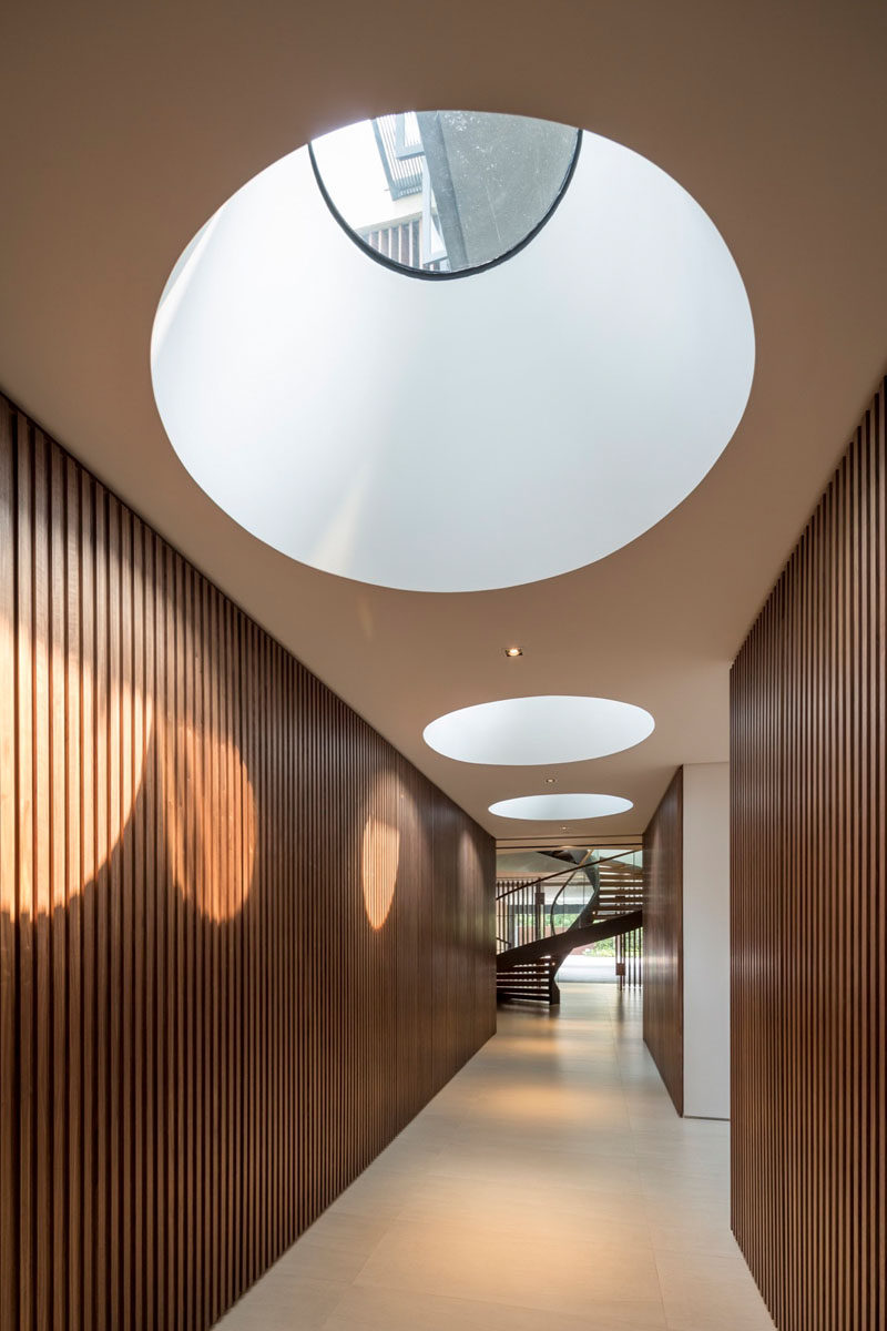 This wood lined hallway has large round skylights to introduce sunlight to the space.
