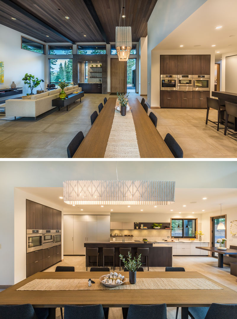 In this modern home, a long dining table separates the living room from the kitchen, and a large pendant lamp anchors the dining area within the open floor plan.