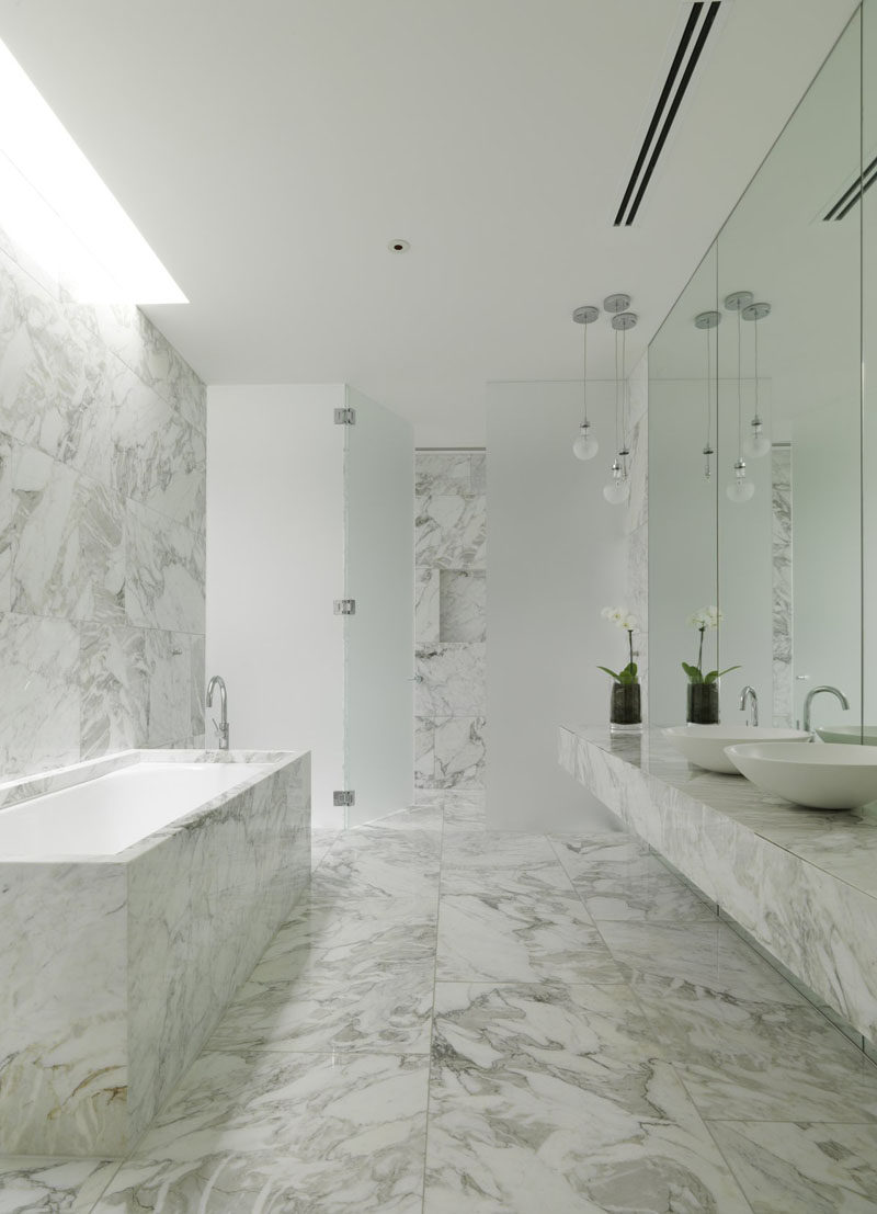 Marble covers the floor, walls, counter, and shower area of this bathroom, keeping it bright, clean, and modern.