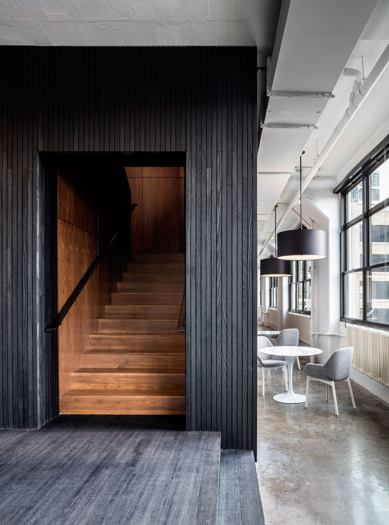 Blackened wood encases a dark walnut staircase in this office.