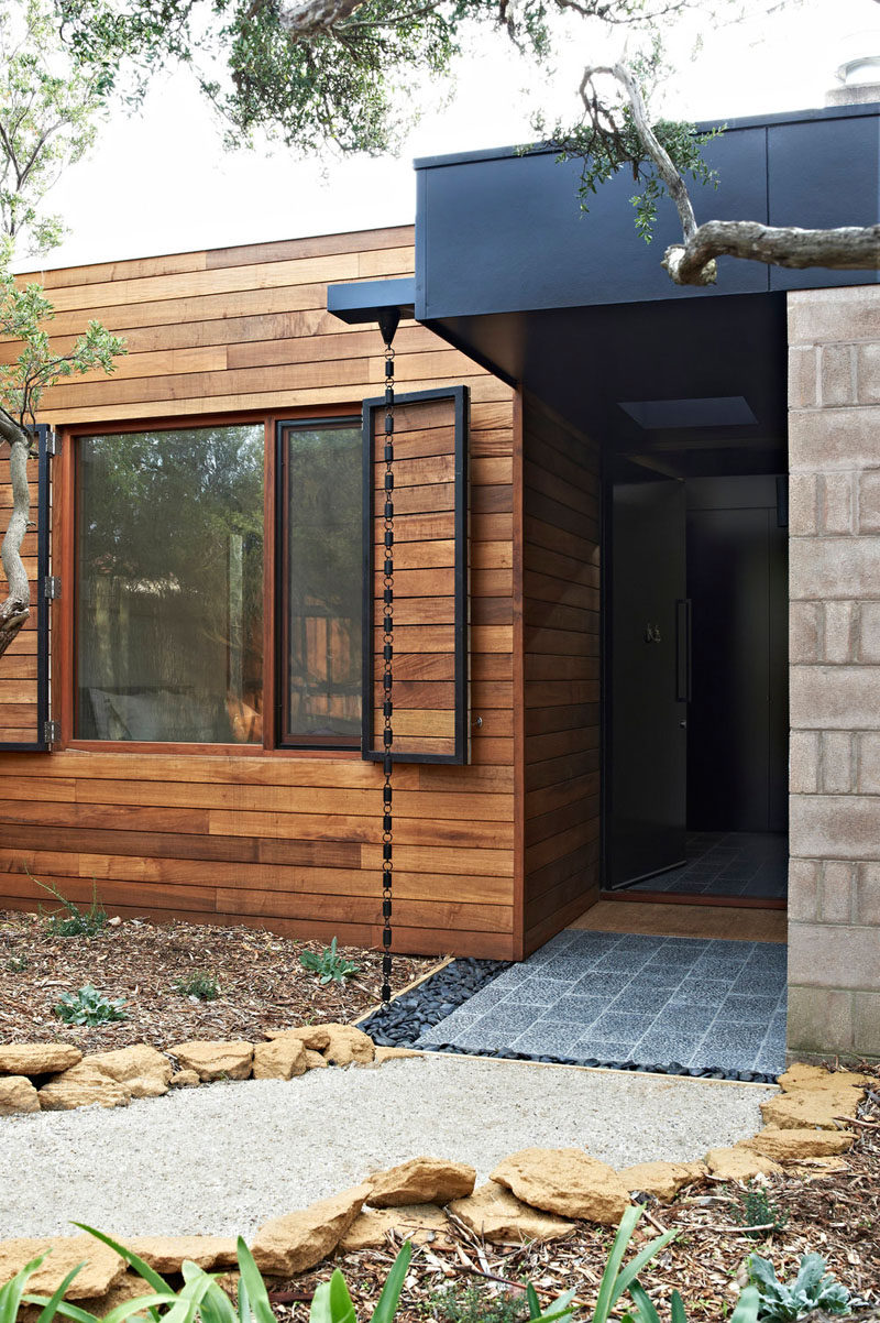 14 Modern Homes That Use Rain Chains To Divert Water // A chunky black chain carries rain water into a bed of rock at the front door of this home creating an industrial look as you walk in.