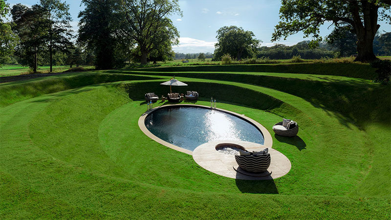 This outdoor space has a circular grassy path that leads to a sunken swimming pool.