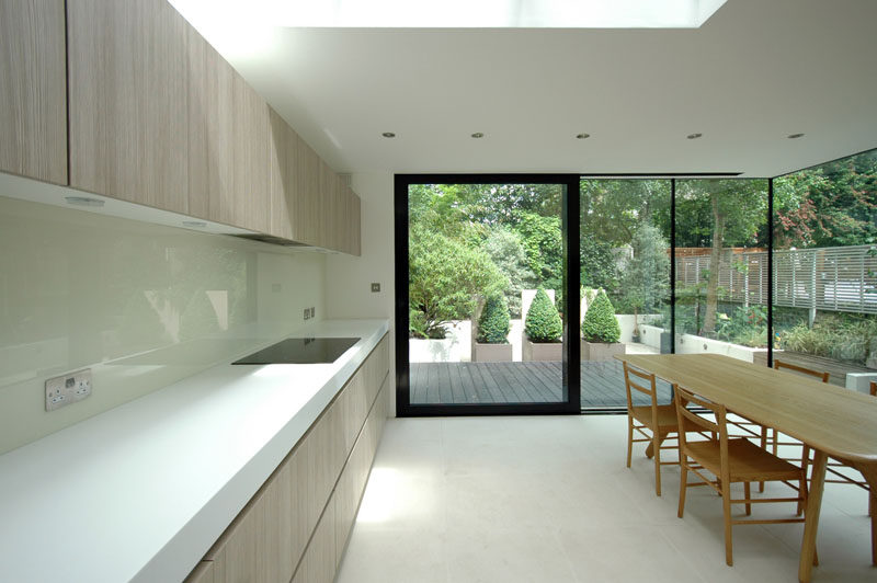 This updated kitchen has light wood cabinetry and white countertops that help to reflect the light from the skylight in the ceiling.