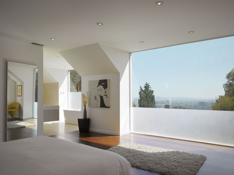 A partially frosted window provides privacy for a modern bedroom and bathroom.