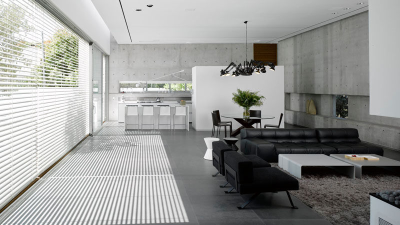 White Venetian blinds cover a wall of windows in a modern concrete house.