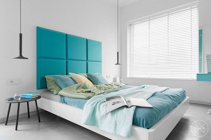 White Venetian blinds cover the large window in a modern bedroom.