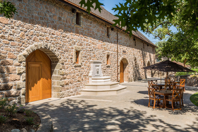 This bar at a vineyard has stone archways and large wooden doors that open up to the courtyard outside.