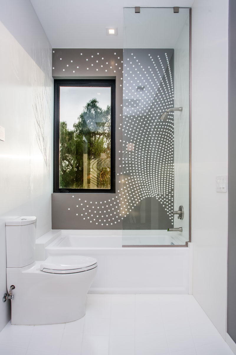 This modern bathroom has artistic tile pattern covering the wall in the shower.