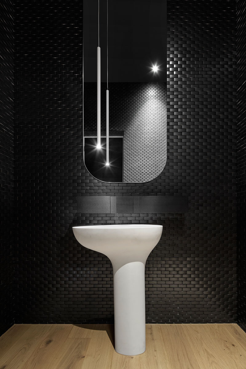 Black tiles create a bold and dramatic look in this modern powder room.