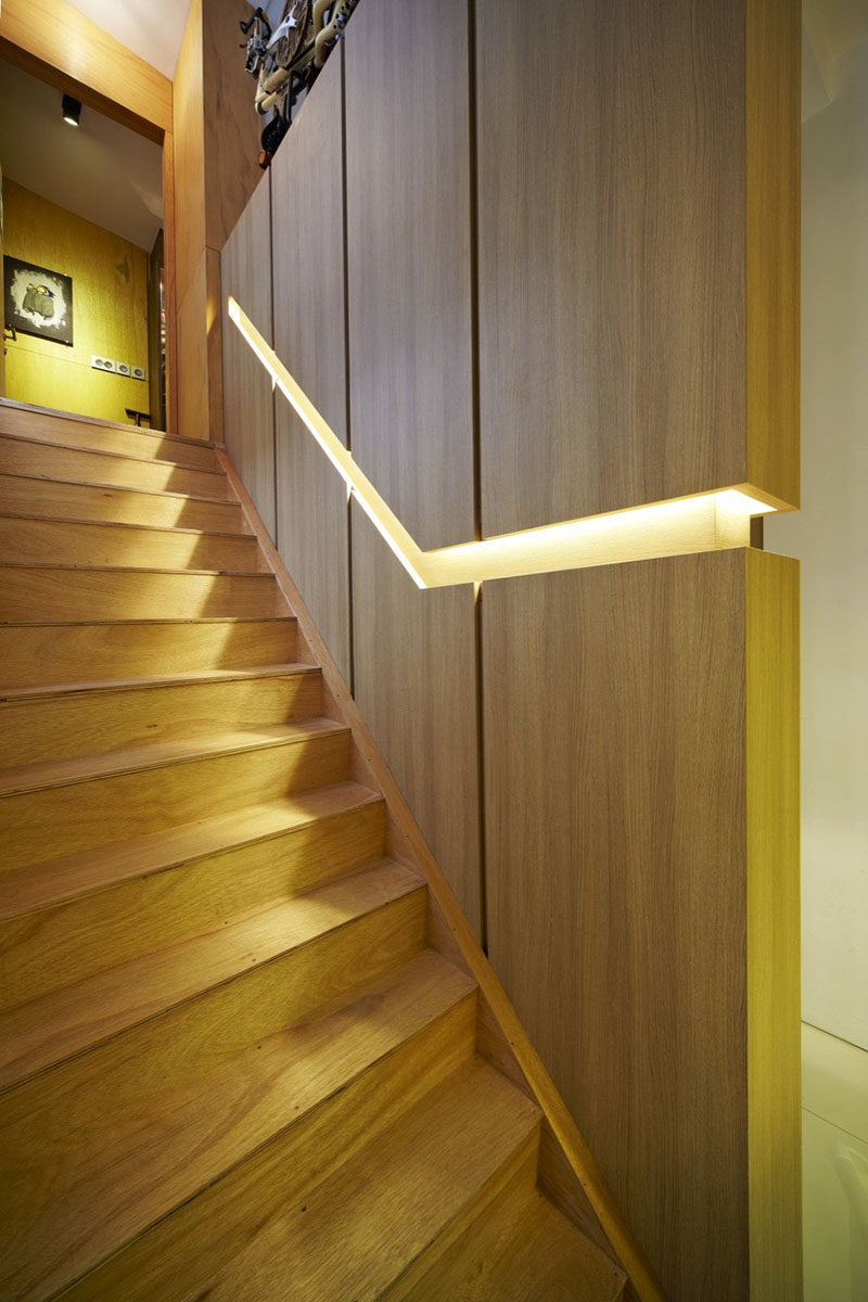 Stair Design Ideas - 9 Examples Of Built-In Handrails // In this Singaporean home, a wooden wall is broken up by the built-in handrail that features hidden lighting. #BuiltInHandrail #HandrailIdeas #HandrailDesign #StairDesign #Handrails