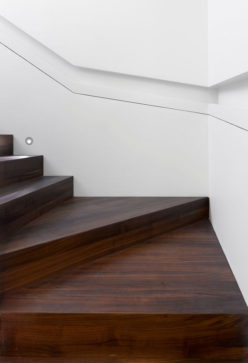 Stair Design Ideas - 9 Examples Of Built-In Handrails // This white wall that wraps around the stairs has a section cut-out of it to house the handrail.  #BuiltInHandrail #HandrailIdeas #HandrailDesign #StairDesign #Handrails