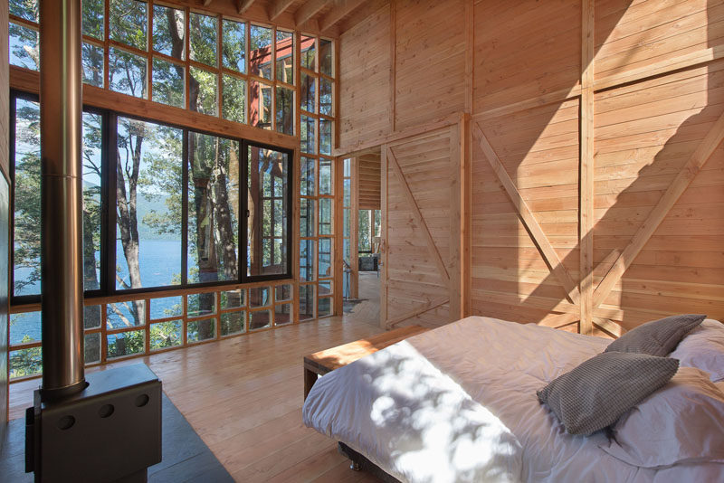 This bedroom with a small fireplace, makes the most of the view by having floor-to-ceiling windows.