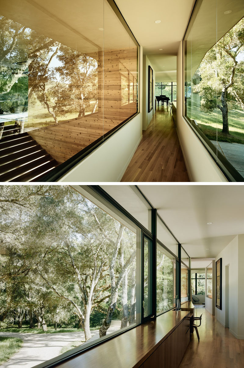 Large windows line this hallway, and a wooden cabinet is interrupted by a small area for a desk.