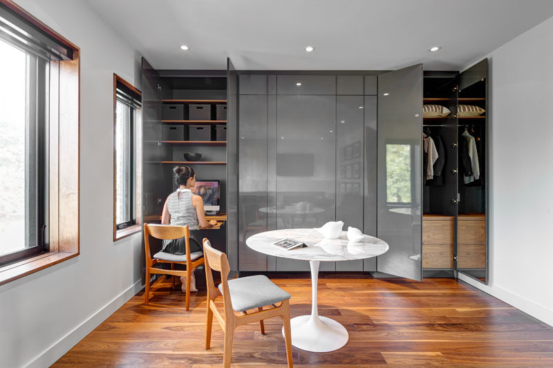 This guest bedroom has been set up as an office with a wall full of cabinetry that provides plenty of storage to the room and hides a small work desk.