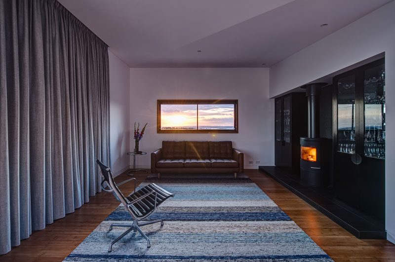 In this living room, the fireplace provides warmth to the home, and the window perfectly frames the view.