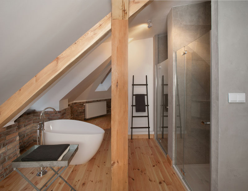 In this open bathroom, there's a standalone bath that has views out of the window, and on the right there's separate boxes for the shower and toilet.