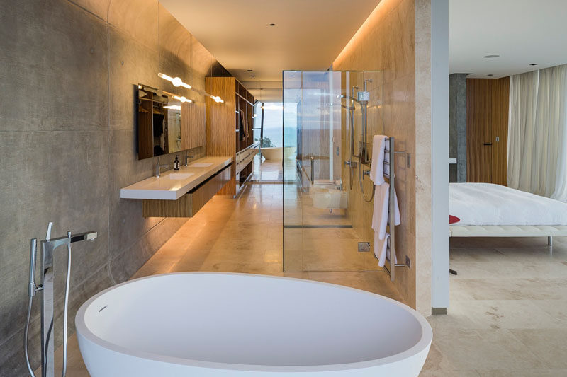 A wall separates the bed from the bathroom in this master bedroom.