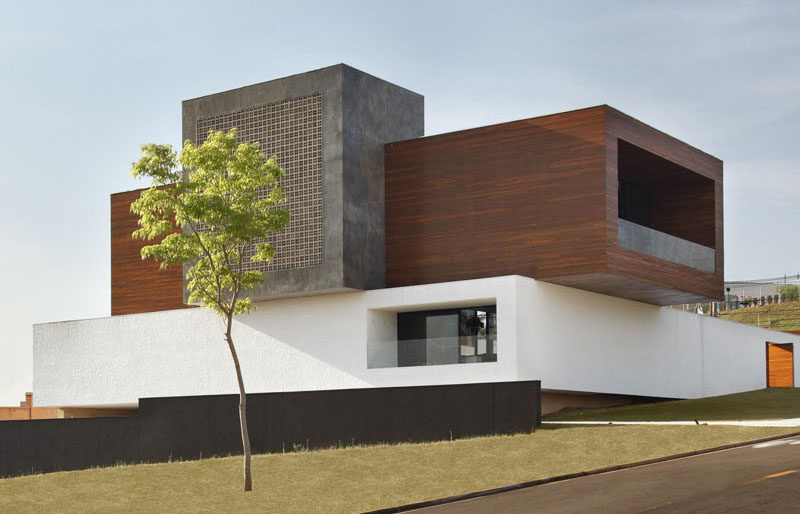 This modern home in Brazil has a Cumaru wood clad concrete box that extends out over the long white exterior wall.