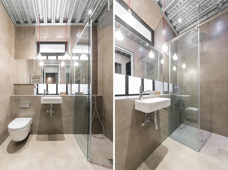 In this bathroom, a small shower is surrounded by glass helping to make the space feel larger, and the metal ceiling and large mirror aids in reflecting the light.