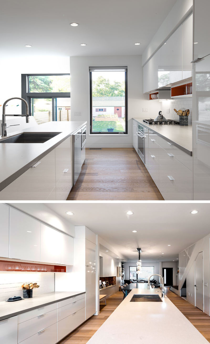 To break up this bright white kitchen, a light gray countertop and colorful shelves under the upper cabinets have been installed. A vertical window provides lots of light and views to the backyard.