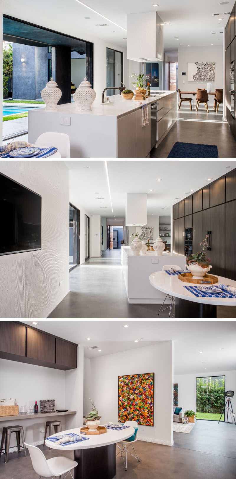 In this modern kitchen, the white kitchen island is a bright contrast to the wall of dark cabinetry behind it. There's also an additional smaller dining area at the end of the kitchen.