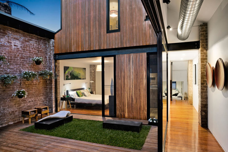 A small courtyard with a grassy patch and hanging planters separates the living area from the master bedroom in this renovated ambulance station.