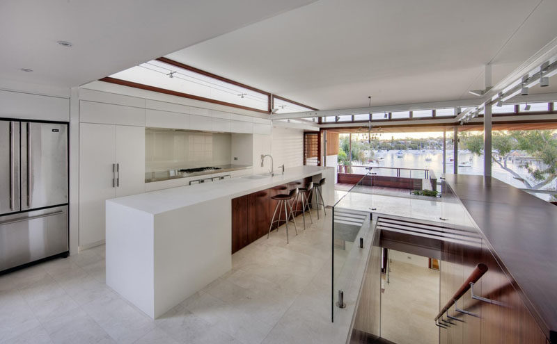 Kitchen Design Ideas - White, Modern and Minimalist Cabinets // The white cabinetry in this kitchen is warmed up with the rich toned wood along the upper windows and on the island.