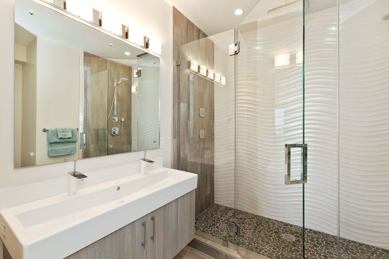 Bathroom Tile Ideas - Install 3D Tiles To Add Texture To Your Bathroom // These wavy tiles along with the pebble like shower floor and the wood details give this bathroom a modern beachy look.