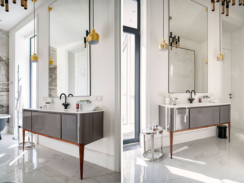 In this bathroom, a vanity with sleek grey cabinetry and only two legs is attached to wall. A tall mirror helps the space to feel even larger than it is.