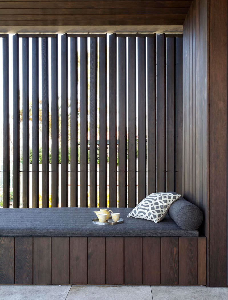 This balcony in an Australian home has a built-in daybed surrounded by dark timber.