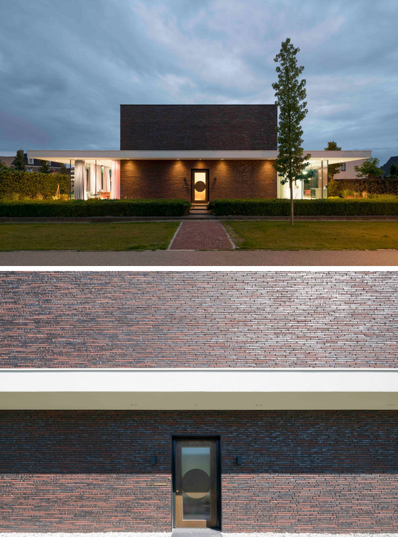 This two-storey home has an exterior of dark bricks, which is broken up by the use of large windows and a wide cantilevered first floor slab.