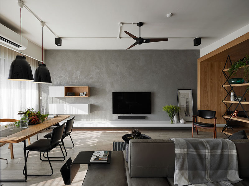 This grey feature wall in an apartment is home to the television and additional floating storage.